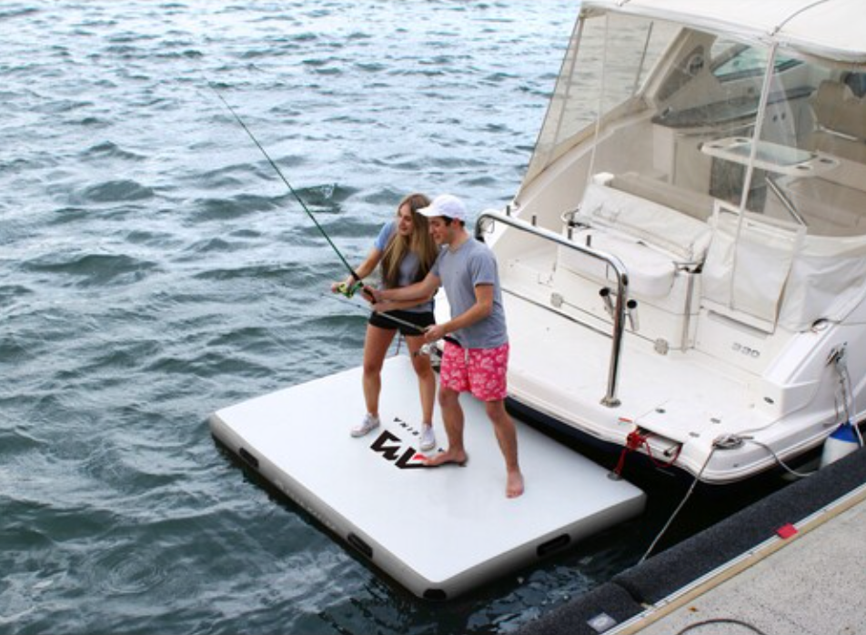 Two people on Aqua Marina Island Inflatable Platform fishing behind a boat.