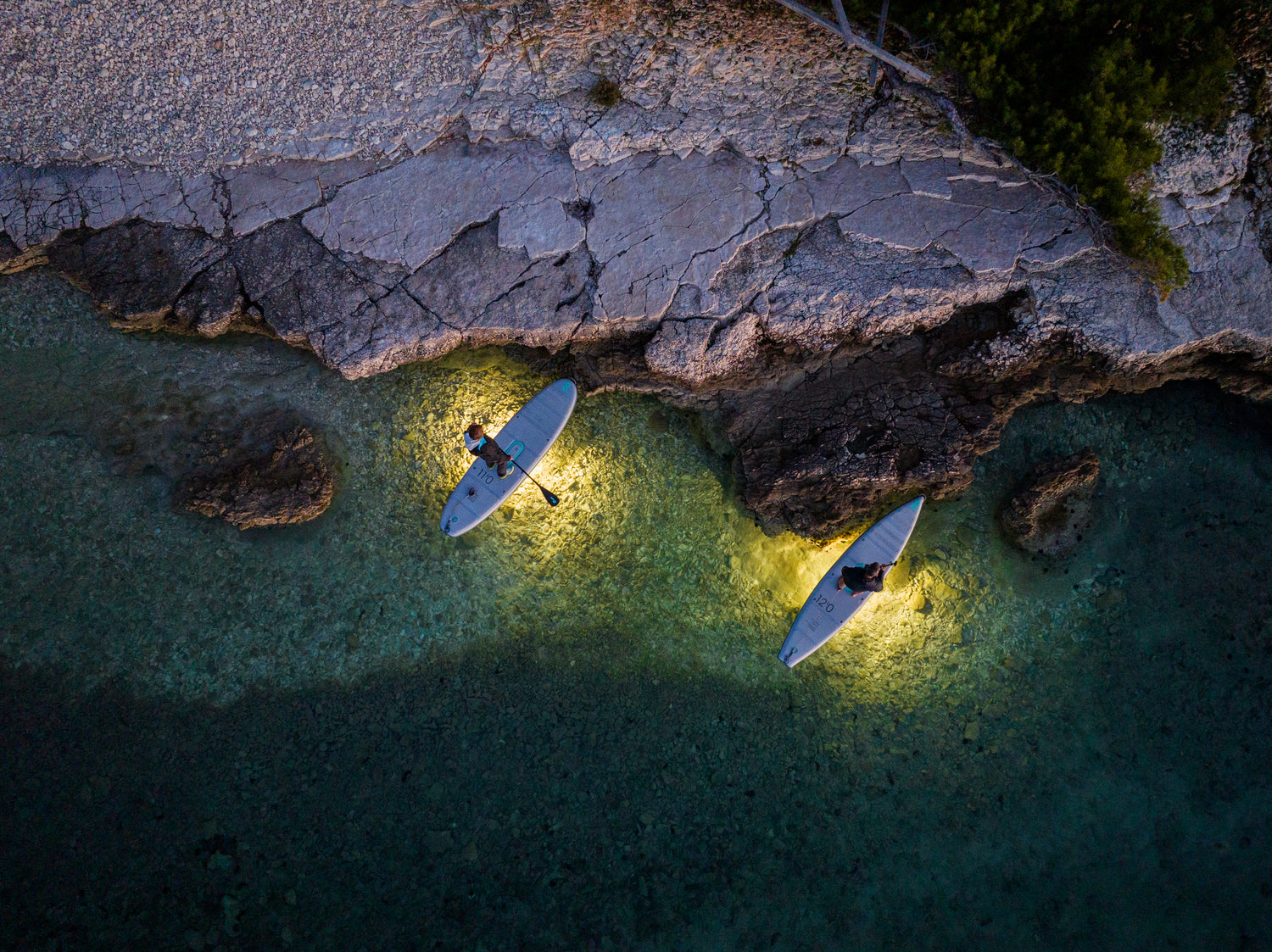 Two SipaBoards iSUP's lights glowing the water under them.