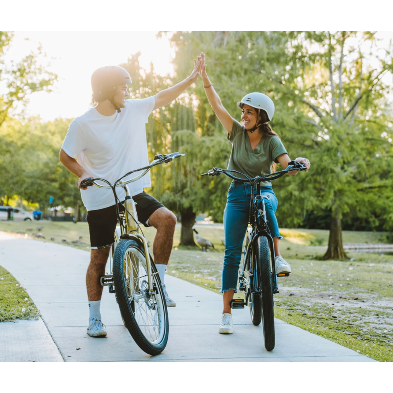 Couple on Denago Cruiser 1 E-Bikes high fiving each other.