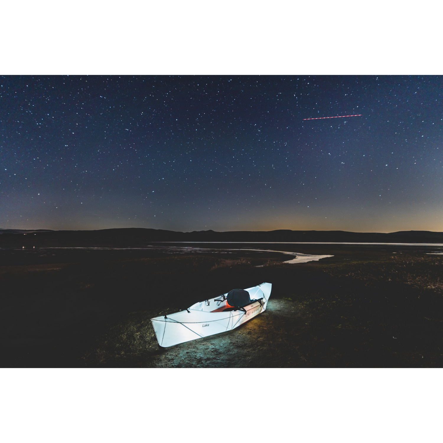 Oru Lake Kayak lit up at night under the stars.