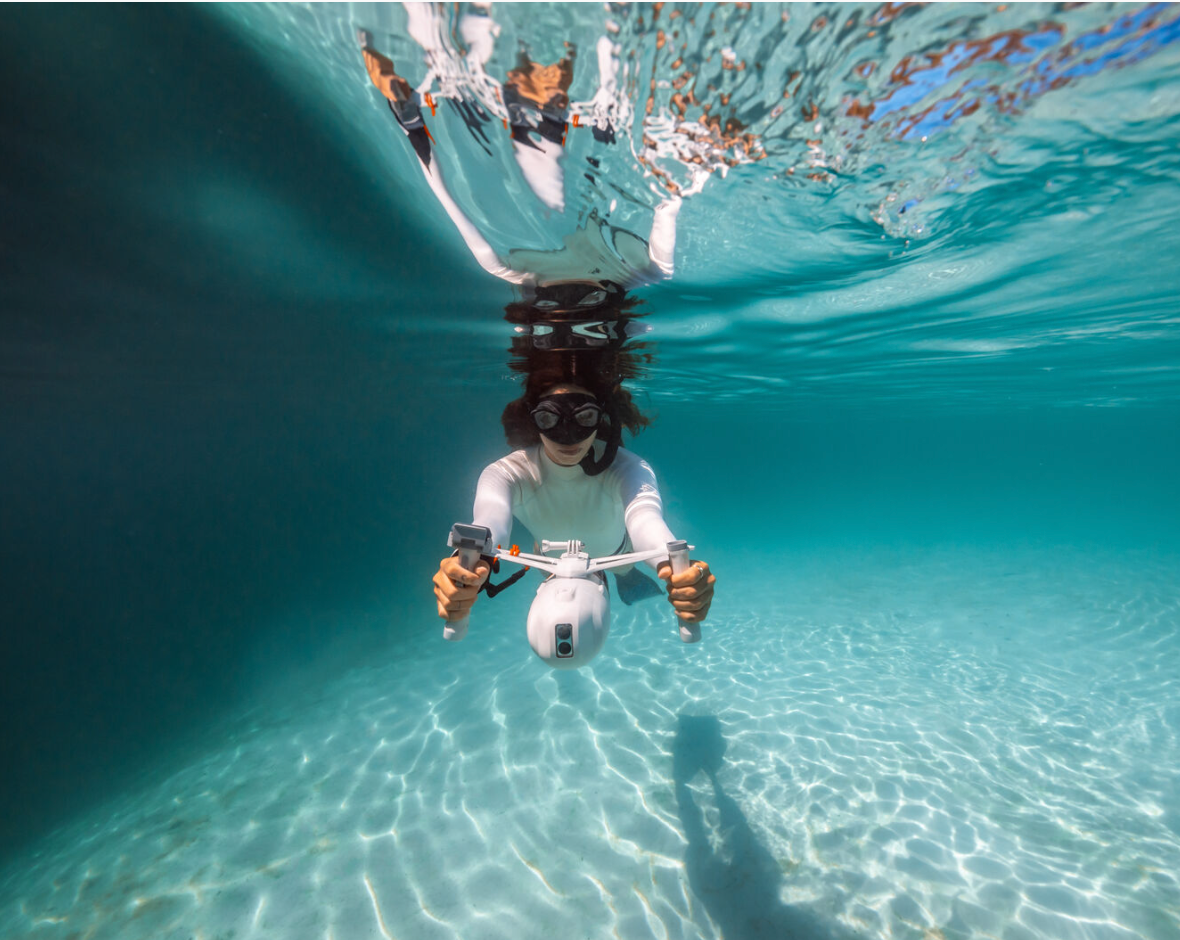 Girl riding an underwater scooter underwater.