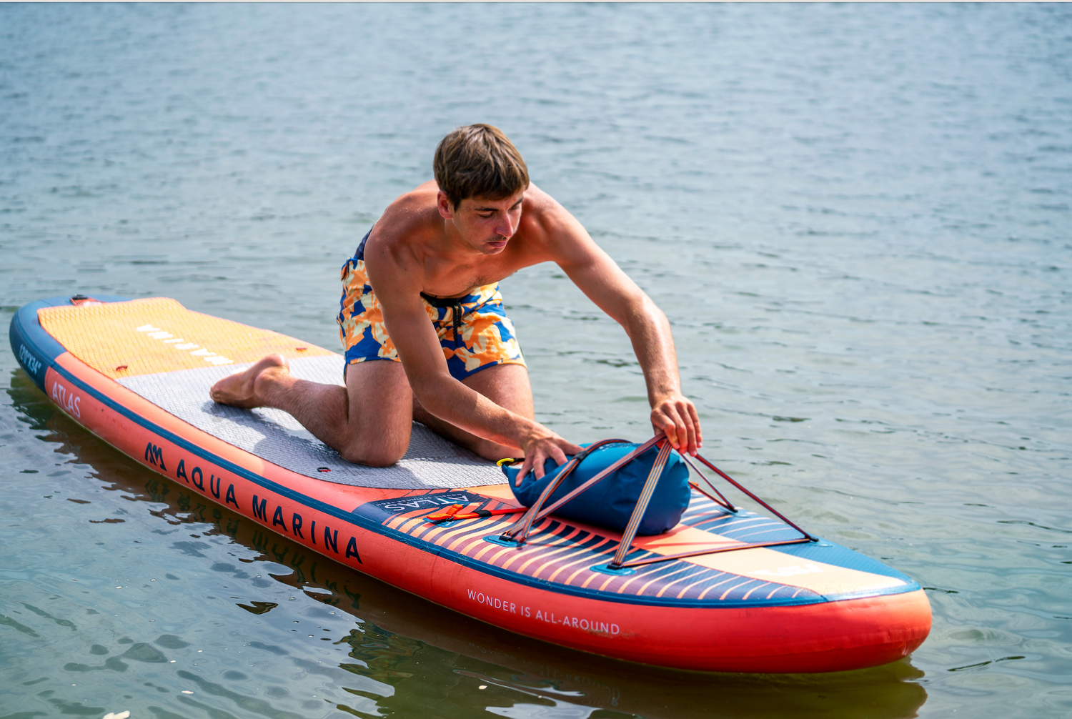 Guy putting bag under front straps of Aqua Marina Atlas out on the water.