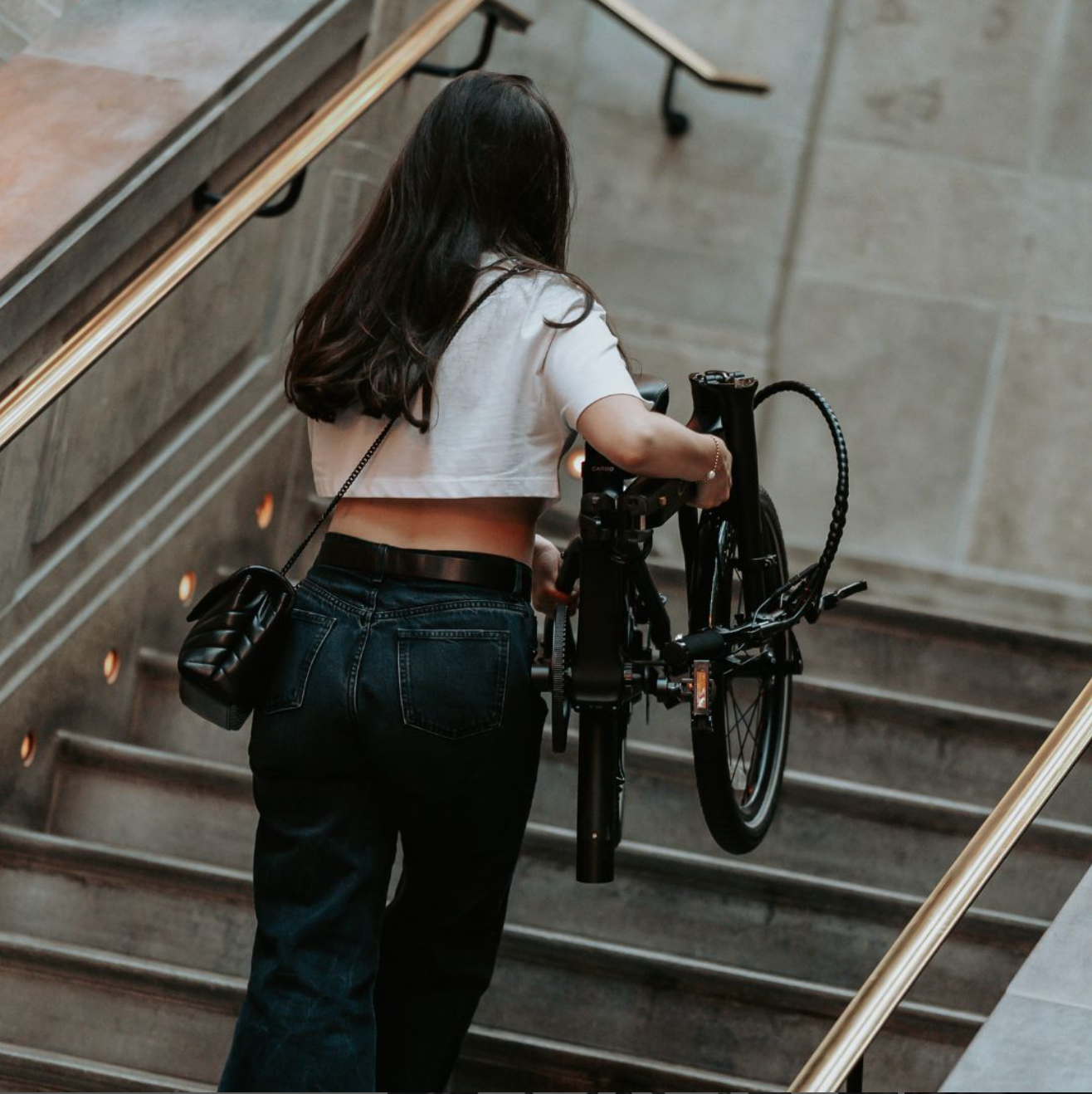 CARBO Model S Girl carrying folded bike up stairs.