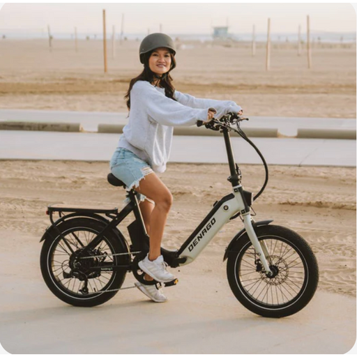 Girl riding white Denago Folding Model 1 E-Bike in an open area on dirt.