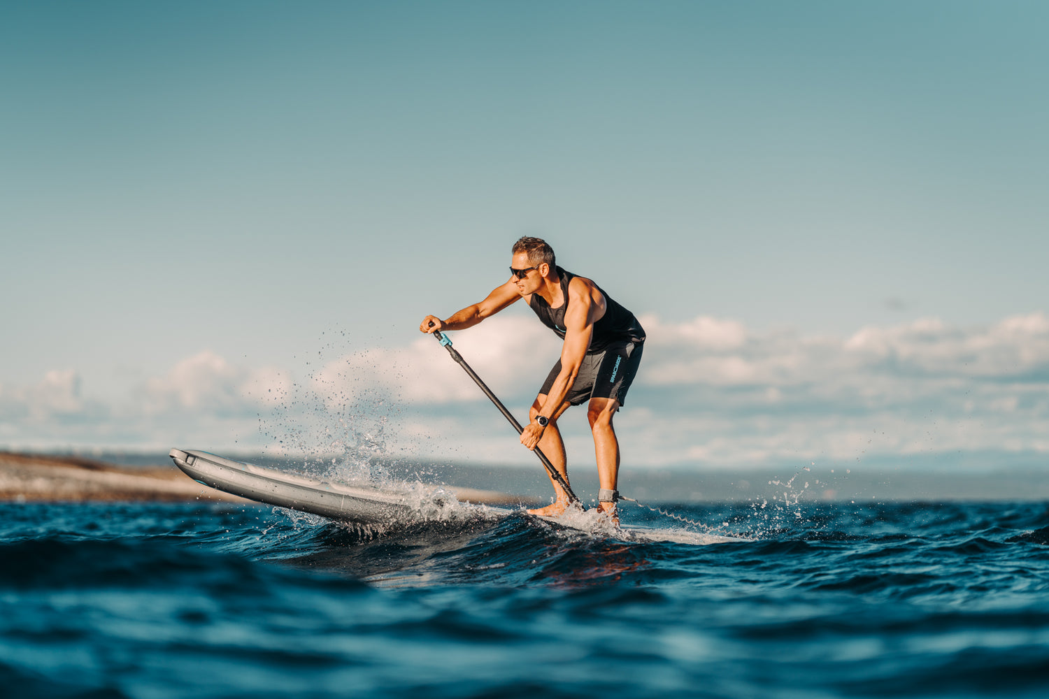 Guy riding through waves on SipaBoards electric SUP. 