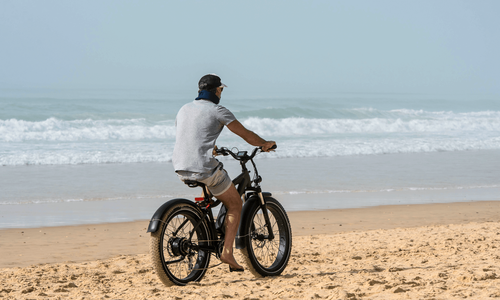 Electric Bike on a beach with a guy riding. Homepage for Current Riders. 