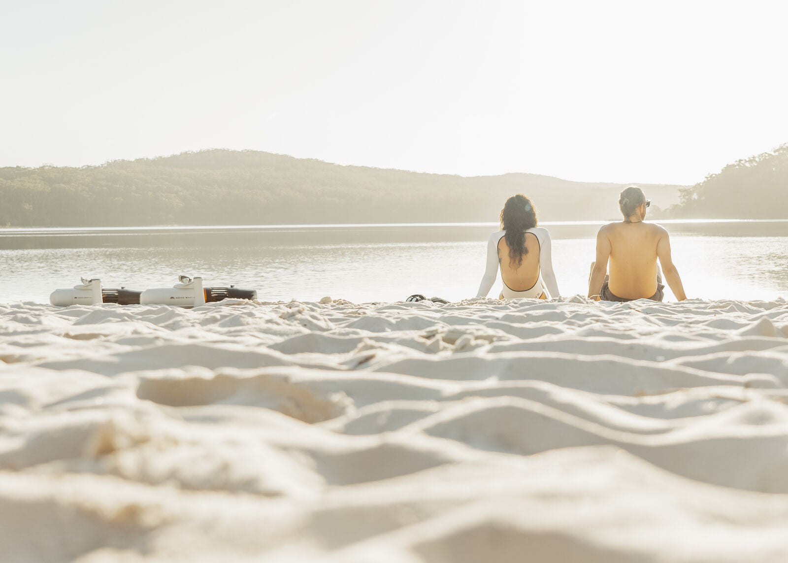 Couple sitting on a beach looking at the water. 