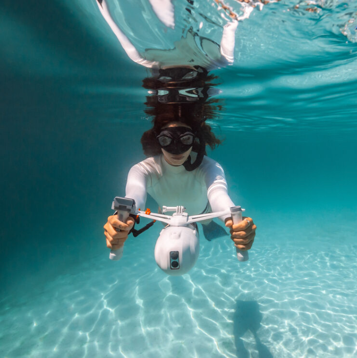 Girl propelling a sea scooter underwater with a snorkel on. 