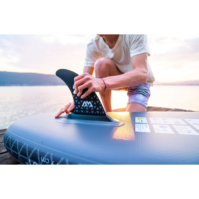 Person putting Aqua Marina Glow SUP fin on board on dock.