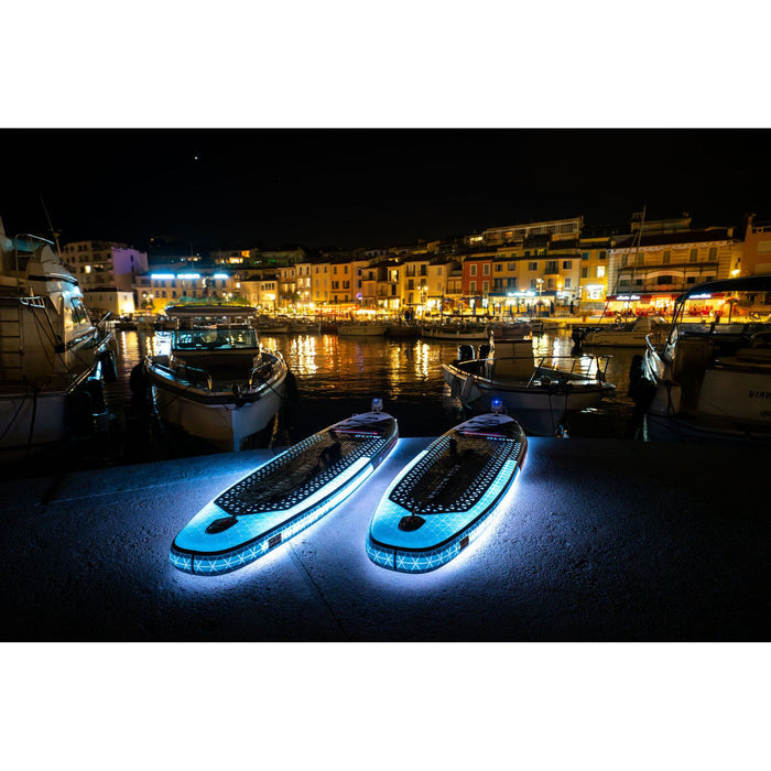 Aqua Marina Glow SUPs with Ambient Light System on at night in marina town. 