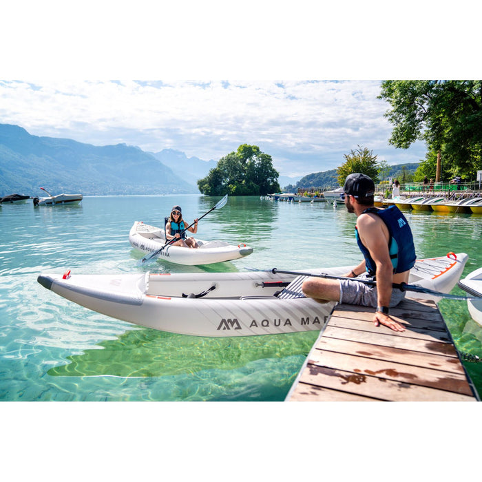 Guy sitting on dock with feet on Aqua Marina Halve Kayak looking a girl in kayak.