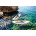 Two people in Halve Kayaks in water next to large rock coastline. 