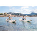 Two people paddling in Aqua Marina Halve Kayaks with country city in background. 