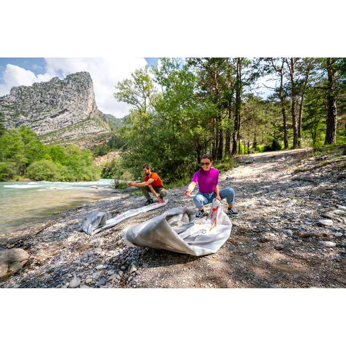 Couple unrolling their Halve Inflatable Kayak on riverbed. 