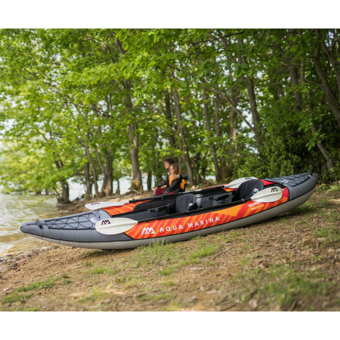 Aqua Marina Memba Kayak on shore with couple sitting behind it.