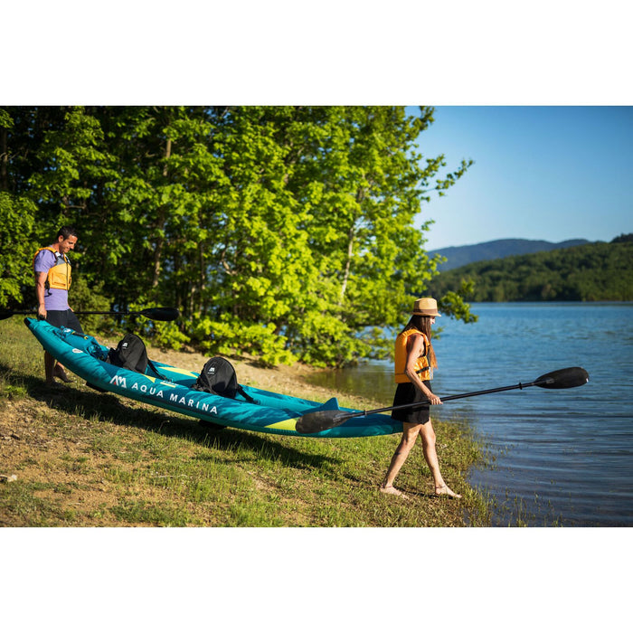 Couple carrying Aqua Marina Steam Inflatable Kayak to lake from shore. 