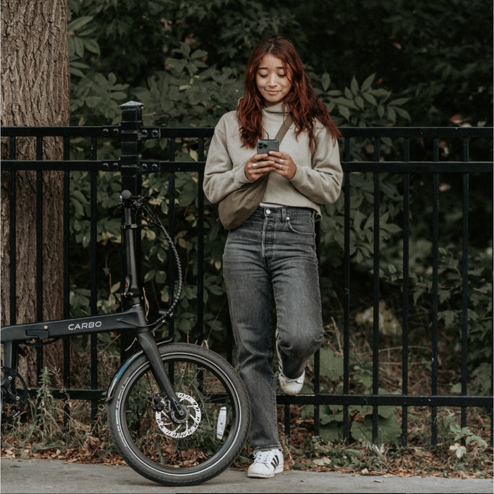 CARBO Model S girl texting while leaning on fence.