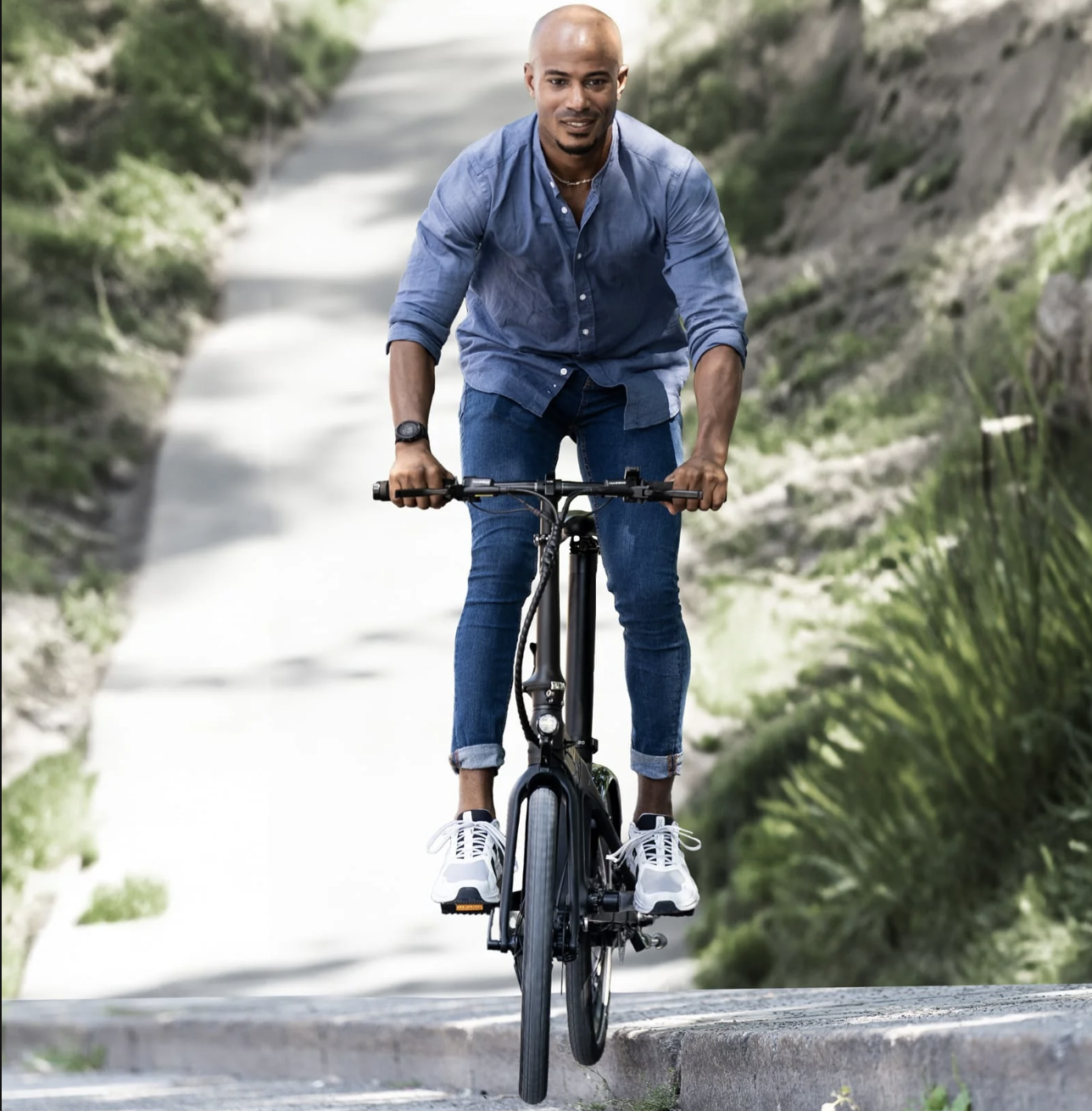 Guy riding CARBO Model X electric bike over curb from sidewalk.