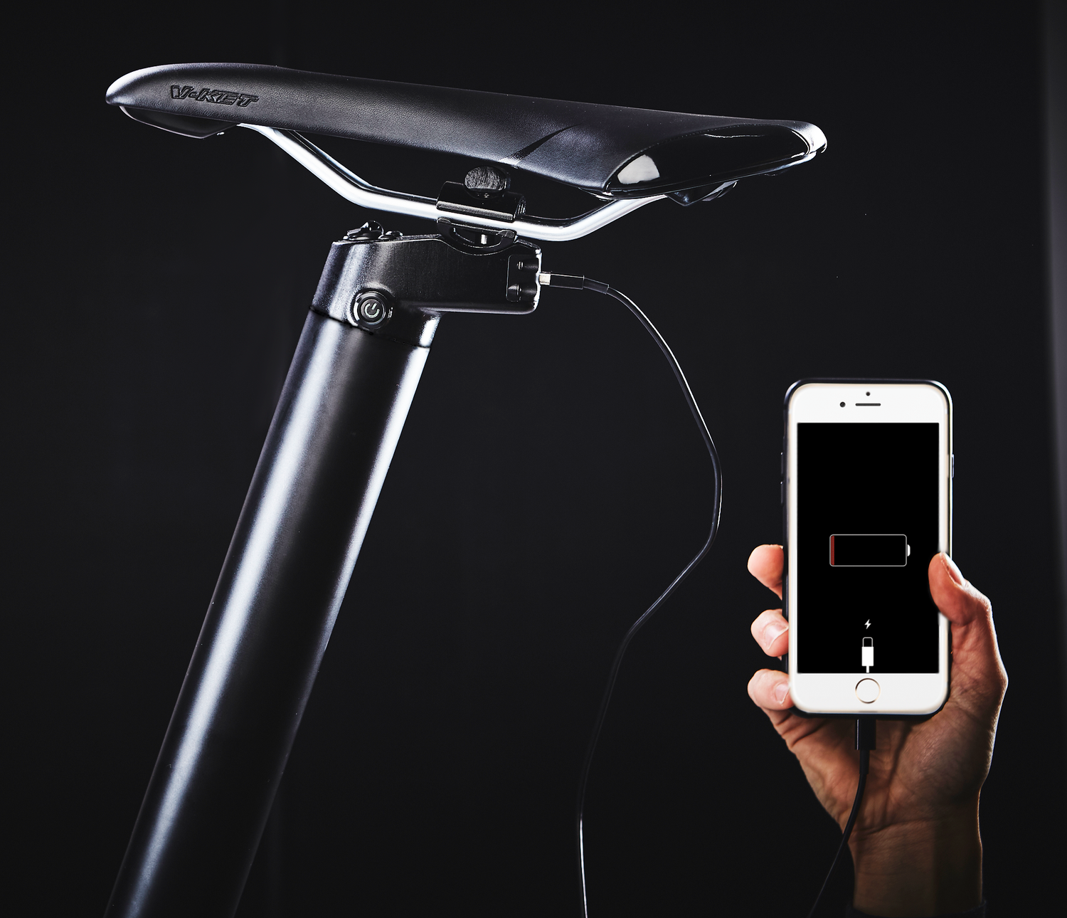 Picture of a hand holding an iPhone showing a low battery and it being plugged in to charge in the seatpost of the CARBO Model S.