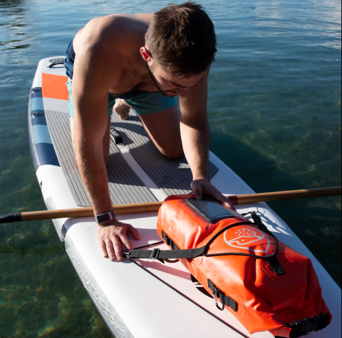 Guy checking phone in Loon Paddle Company 15 Liter Dry Bag on iSUP.