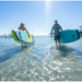 Girl carrying a Jimmy Styks Neptune iSUP into the water with a guy carrying his own.
