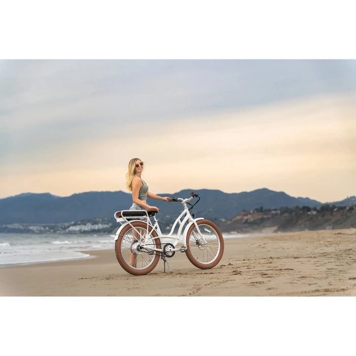 Girl on a beach with Priority Bicycles White E-Coast step-over. 