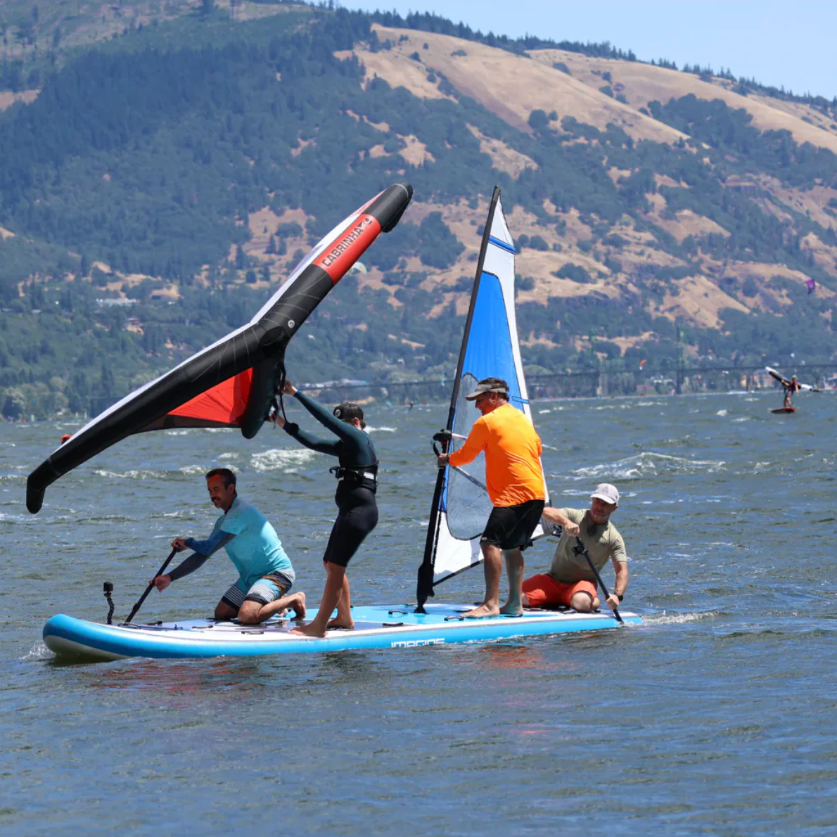 Group of men windsurfing on the Imagine Surf Invader iSUP out on the water.