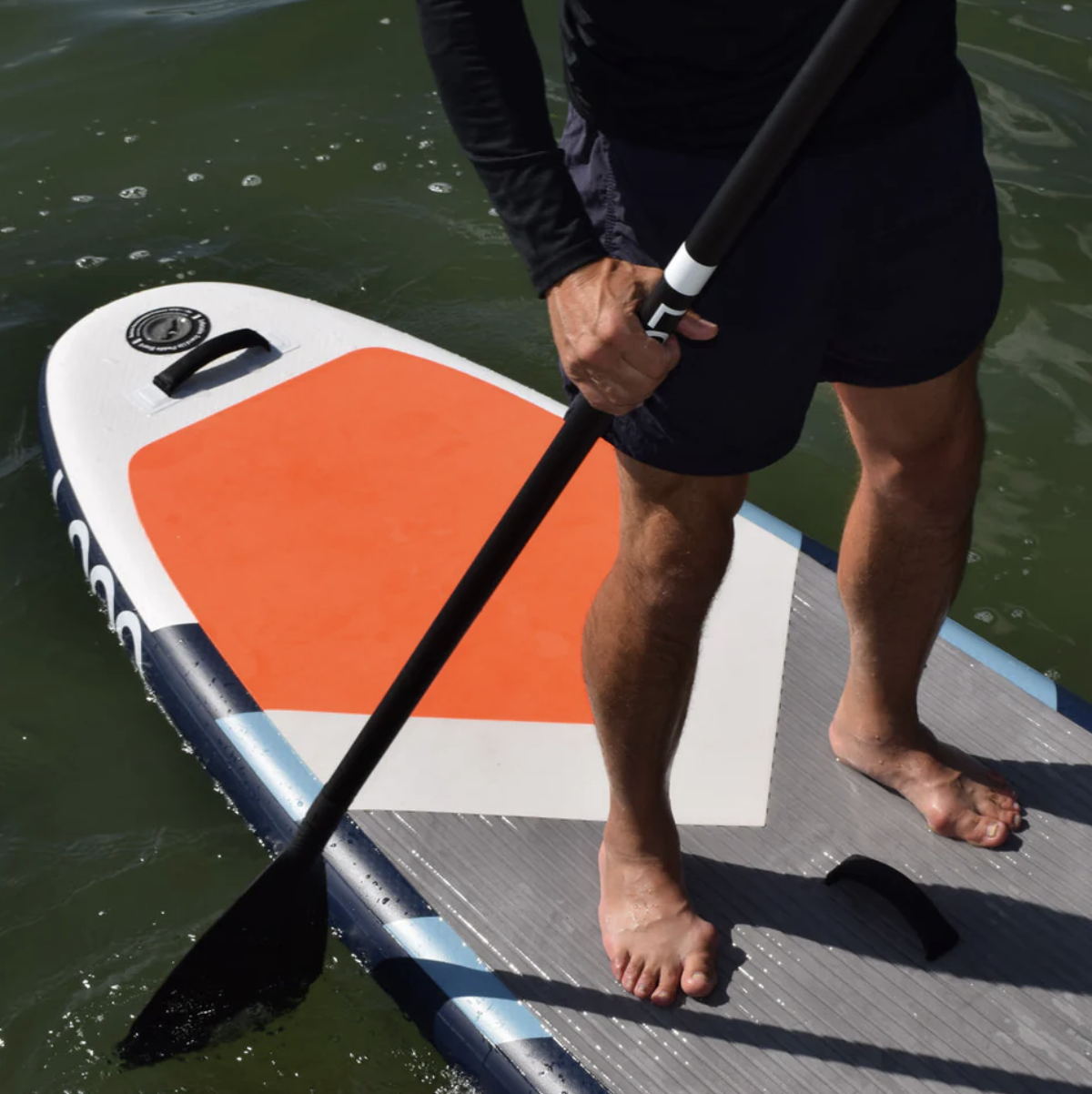 Guy on iSUP holding a Loon Paddle in the water. 