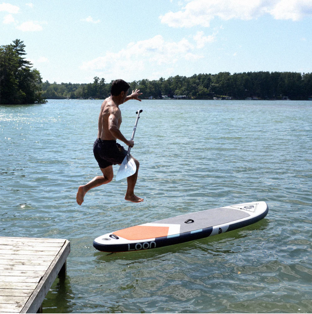 Guy jumping off dock to Loon Paddle Company Feather Light Standard iSUP.