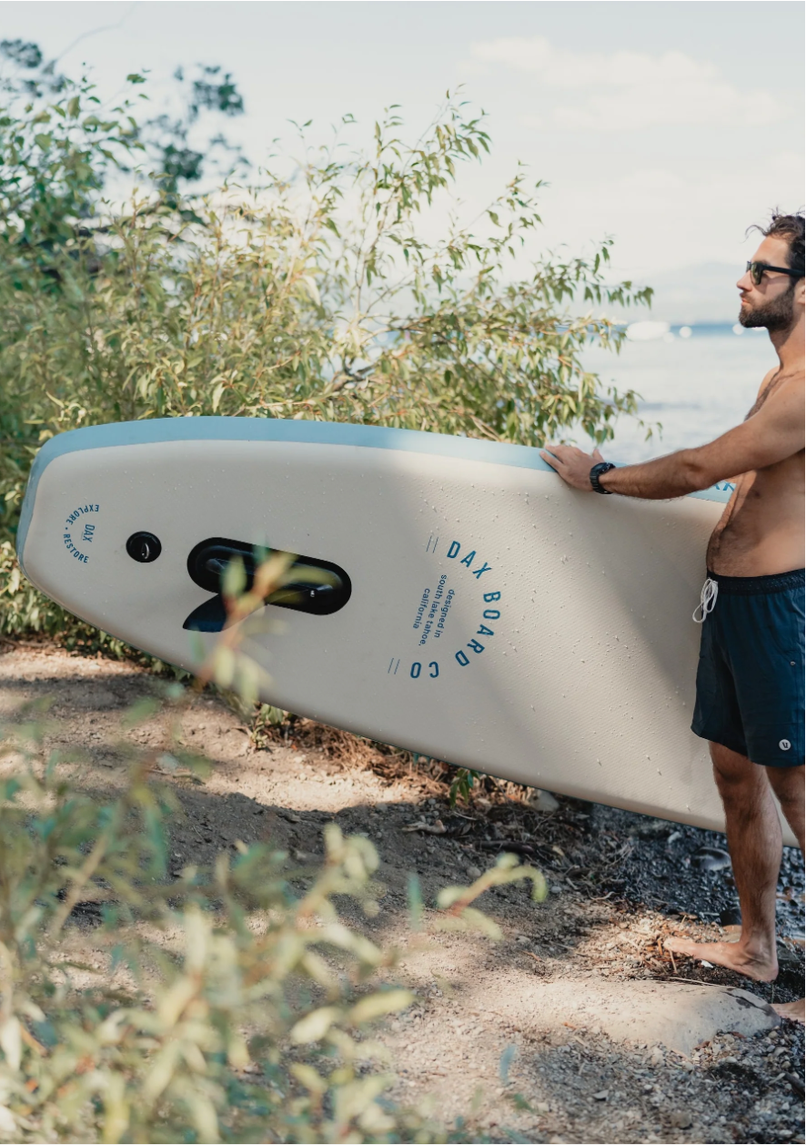 Guy walking with a Dax Board Co. Air High Tide iSUP on a trail. 