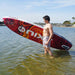 Guy standing in front of red NIXY Venice G5 Inflatable Stand Up Paddle Board in the water.
