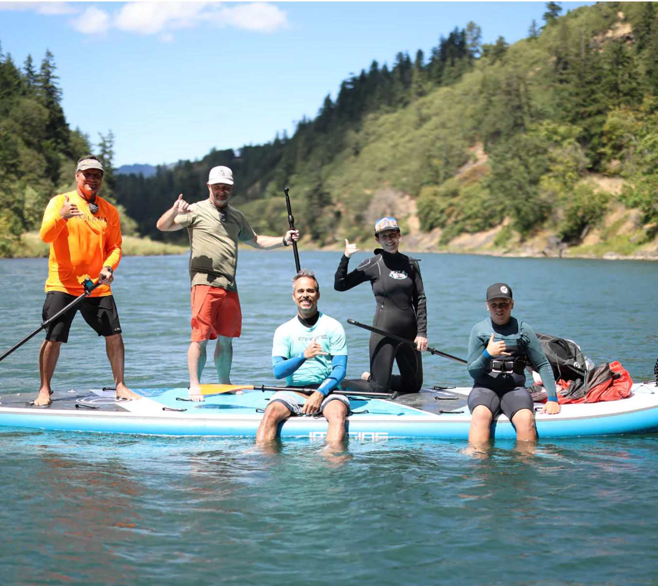 Group on the Imagine Surf Invader Inflatable SUP out on the water with paddles posing for the camera.
