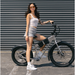 Woman standing next to a JackRabbit MG Renegade electric bike against a gray background.
