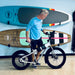 Guy standing with a Silver JackRabbit Renegae eBike with POP Board Co. SUP's behind him on the wall in Fort Myers Beach.