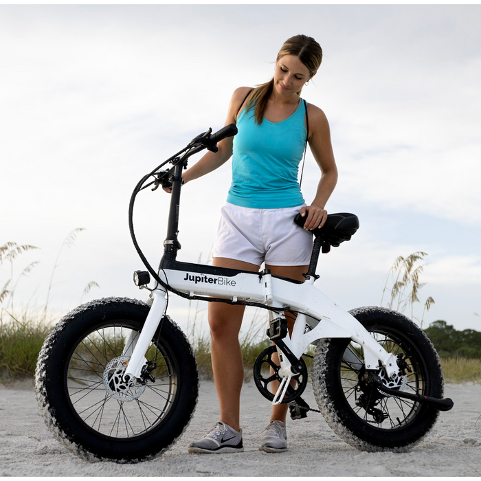 Girl at a beach with Defiant Fat Tire Jupiter Bike folding ebike. 