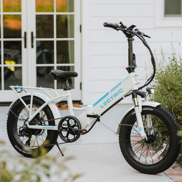 Lectric XP Step-Thru 3.0 White eBike parked in front of french doors.