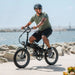 Gury riding Lectric XP Lite 2.0 JW Black Long-Range eBike near the beach.