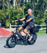Man riding Lectric XP4 folding electric bike on paved path with palm trees in background.