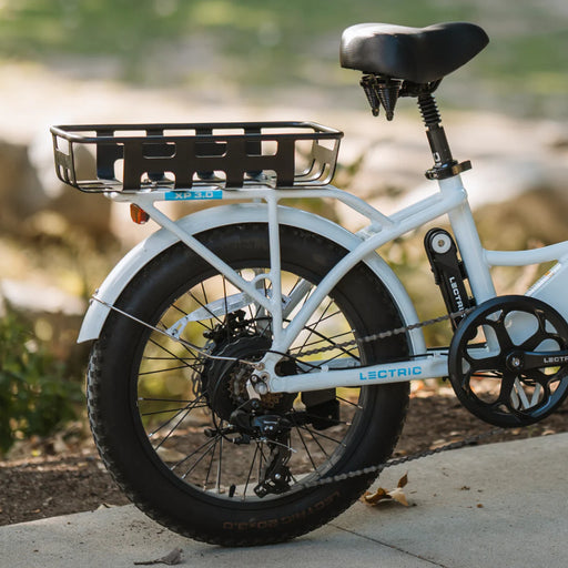 White electric bike with a black basket on a blurred natural background