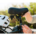 Lifestyle photo of the Lectric Step-Thru Comfort Package on a bike with a white helmet sitting on rear rack next to it.