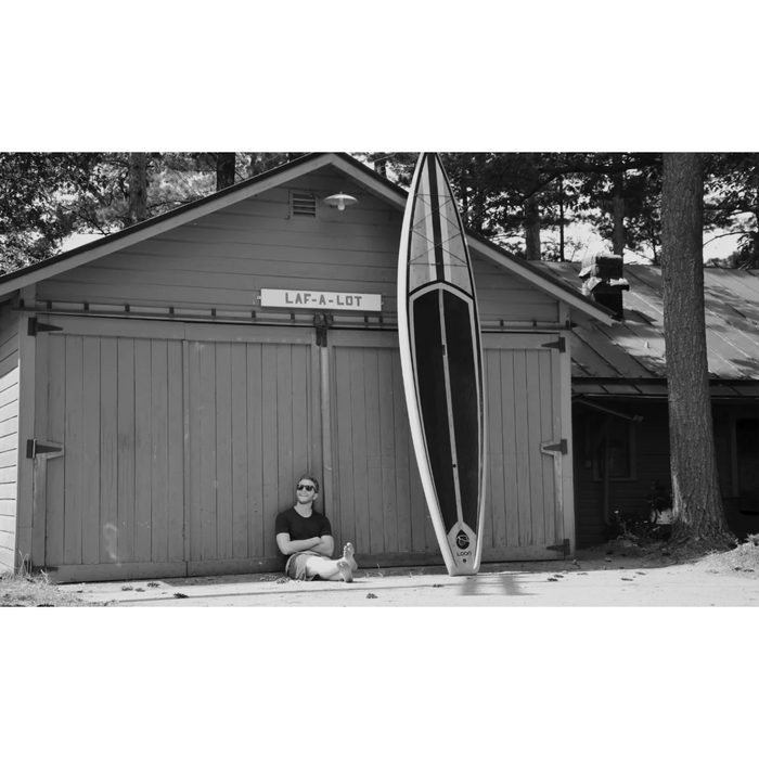 Loon Paddle Company Building With SUP Standing Against It and Guy Sitting On Ground