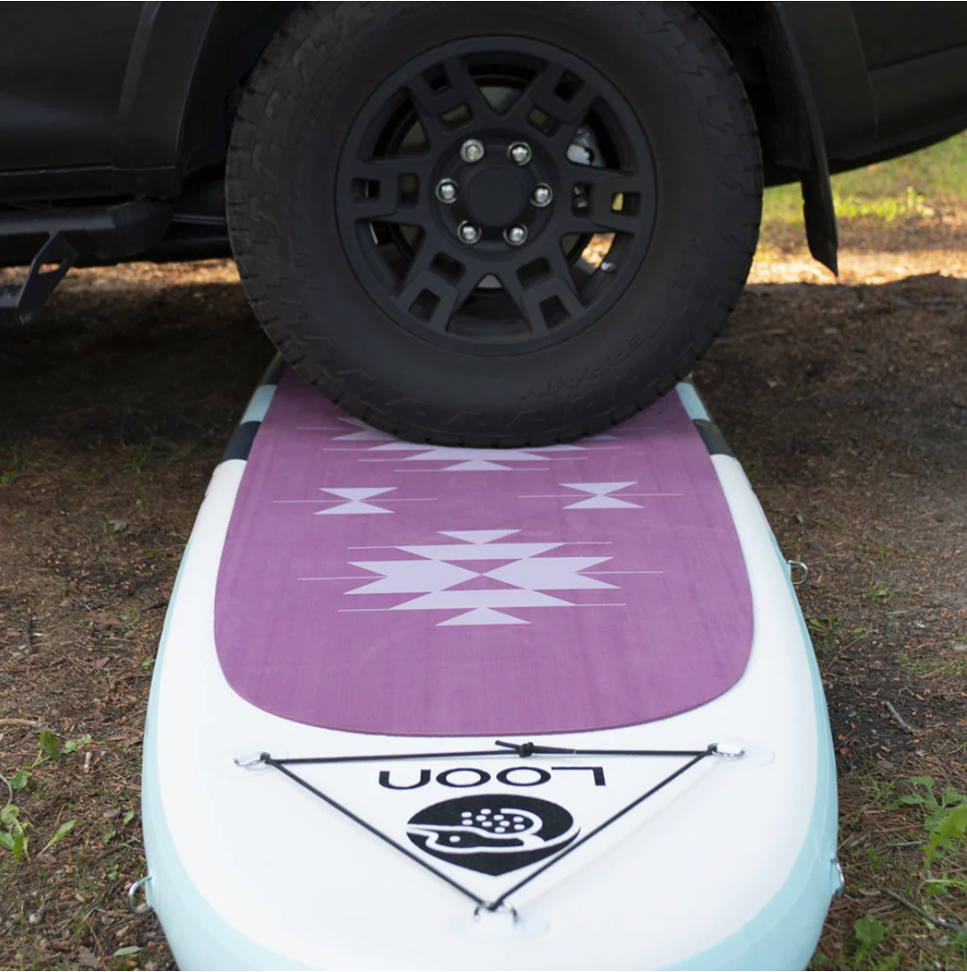 Truck driving over Loon Paddle Co inflatable SUP.