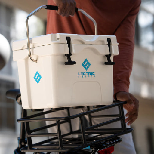 Man putting a Lectric Hard Cooler in a basket on the back of a bike.