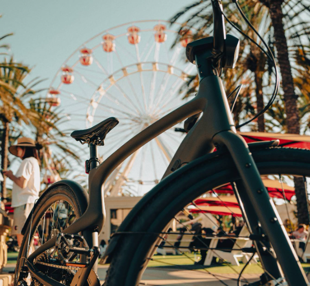 The Urtopia Carbon 1 Pro eBike in front of ferris wheel and palm trees.