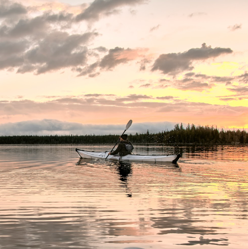 Person paddling an Oru Coast XT Kayak at sunset.