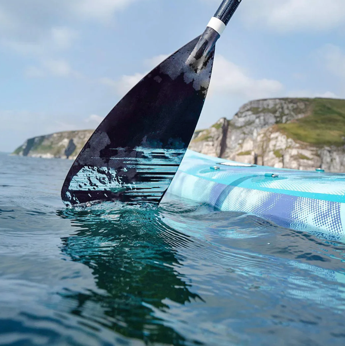 Inflatable paddle board with paddle in water with reflection off water. 