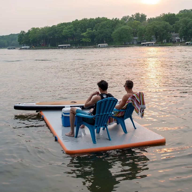 Two guys sitting on chairs floating on ParadisePad Inflatable Mat.