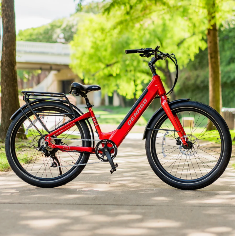 A parked red Denago City Model 3 Step-Thru eBike with trees in the background.