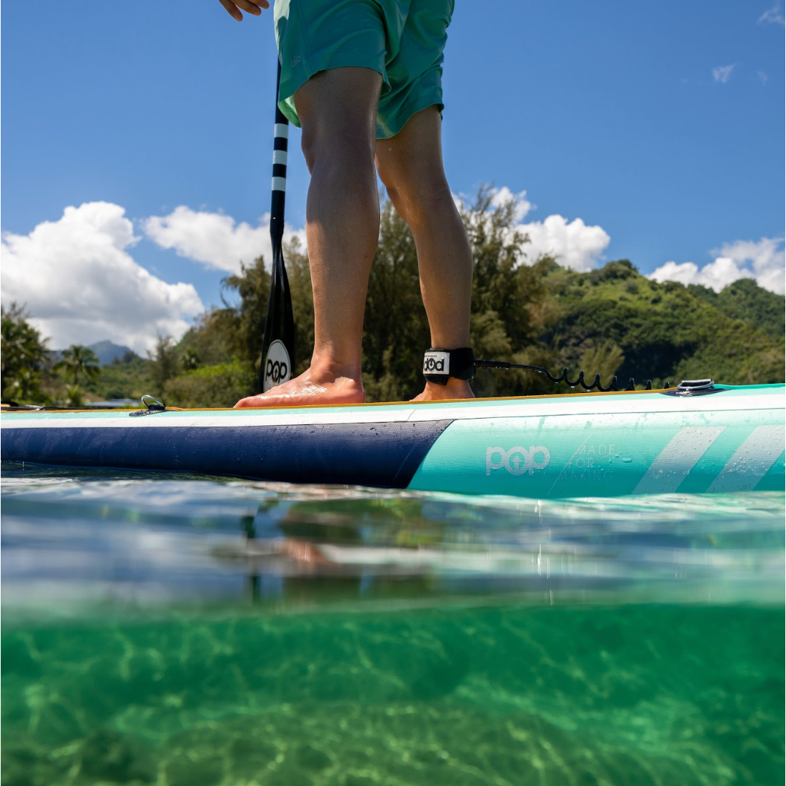Picture of a man's legs standing on a POP Yacht Hopper Paddle Board out on the water.