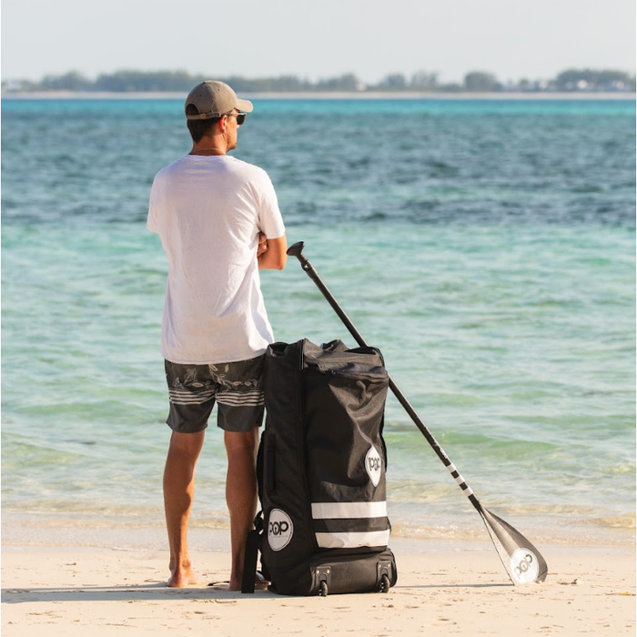 Guy on beach with POP Board iSUP carry backpack with paddle.